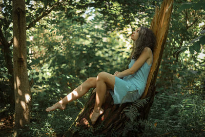 Man sitting on tree trunk in forest