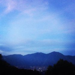 Scenic view of silhouette mountains against blue sky