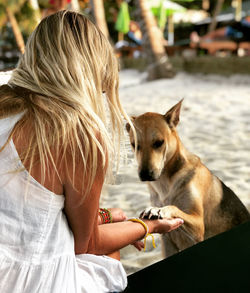 Woman playing dog while sitting outdoors