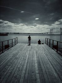 Rear view of people on pier at sea against sky