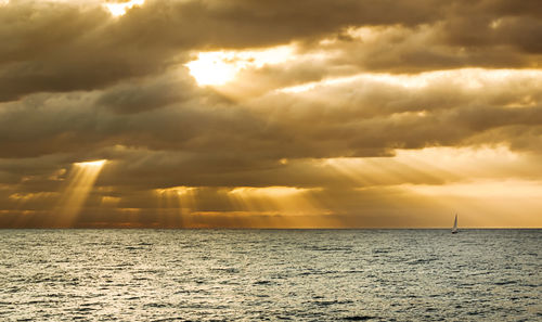 Scenic view of sea against dramatic sky during sunset