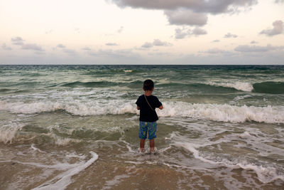 Rear view of little boy standing on beach