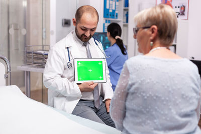 Portrait of young man using digital tablet while standing in hospital