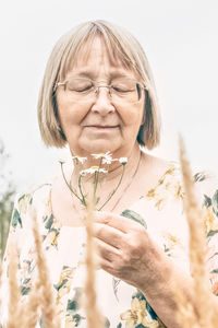 Portrait of an elderly woman holding a bouquet of flowers, smelling the scent of daisies. autumn.