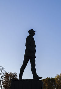 Low angle view of silhouette statue against clear blue sky