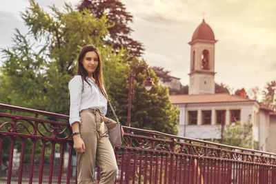 Portrait of beautiful woman standing by railing 