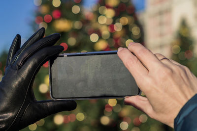 Cropped hand of woman holding smart phone standing outdoors