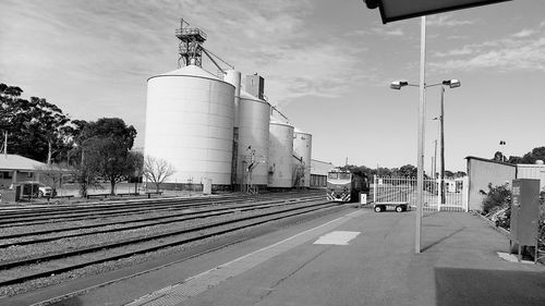 Railroad tracks by street in city against sky