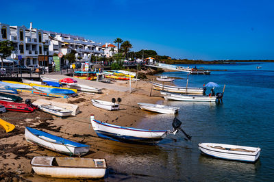 Boats moored on beach against clear blue sky