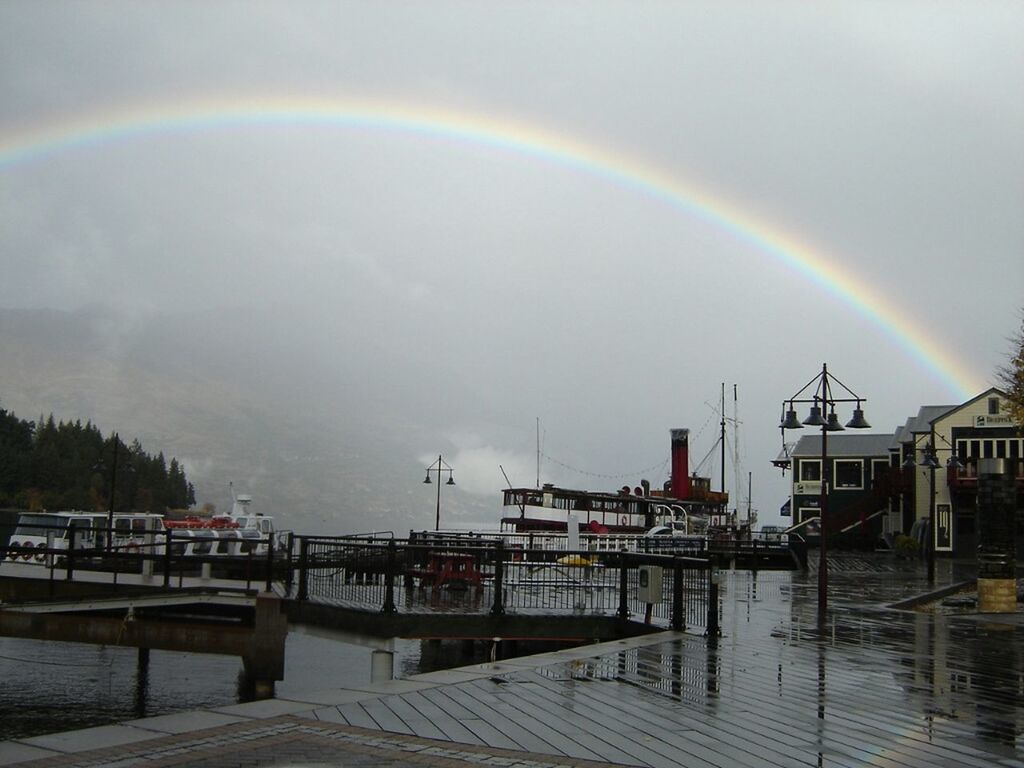 water, sky, cloud - sky, scenics, sea, nature, tranquility, reflection, beauty in nature, built structure, tranquil scene, cloudy, weather, waterfront, pier, outdoors, rainbow, cloud, nautical vessel, idyllic