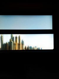 Silhouette buildings against sky seen through glass window