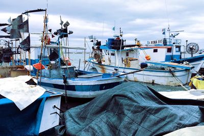 Trawlers moored at harbor in sea against sky