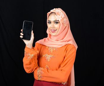 Mid section of a woman using smart phone against black background