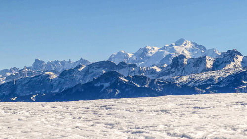 Scenic view of snowcapped mountains against clear blue sky