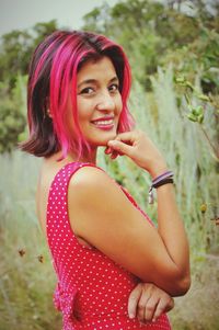 Portrait of smiling woman with pink hair standing on field