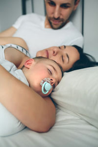 Family sleeping on bed at home