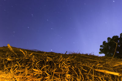 Close-up of hay bales on field against sky at night