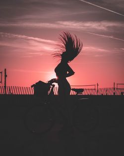 Silhouette woman standing by railing against sky during sunset