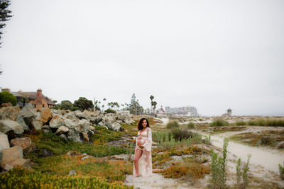 Young pregnant woman posing at beach in sheer dress