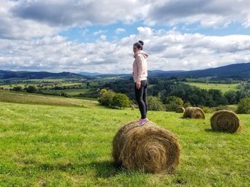 Full length of hay bales on field against sky