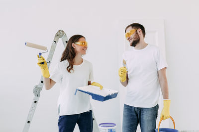 Happy smiling married couple engaged in renovation repair in the room of the house preparing to move