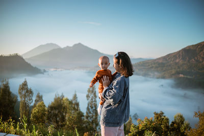 Young woman standing against mountain