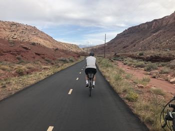 Rear view of man riding bicycle on road