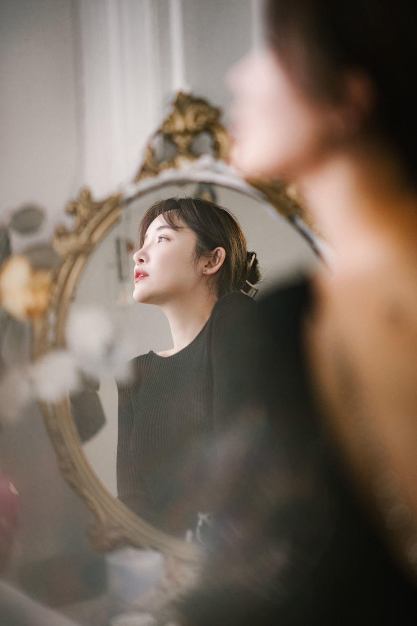 PORTRAIT OF A YOUNG WOMAN WITH REFLECTION IN MIRROR