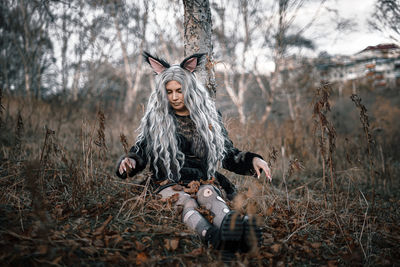 Portrait of young woman sitting on field in forest