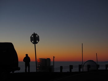 Silhouette of man standing at seaside during sunset