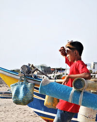 Young man wearing sunglasses sitting against clear sky