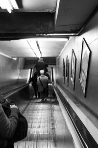 Rear view of woman standing on escalator at subway station