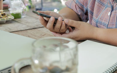 Midsection of man using mobile phone on table