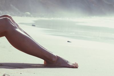 Low section of woman relaxing at beach