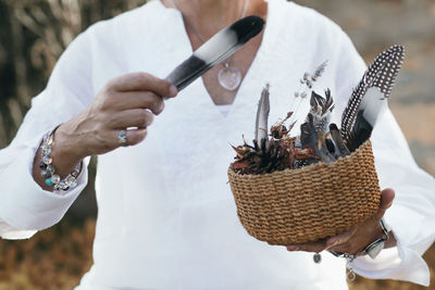 Midsection of man holding feather in container