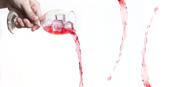 Close-up of hand pouring juice over white background