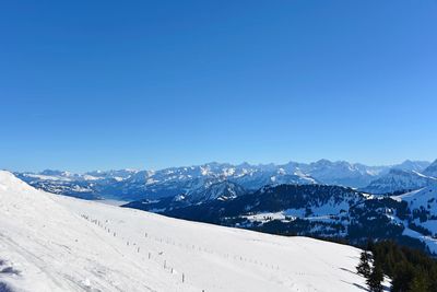 Scenic view of snowcapped mountains against clear blue sky