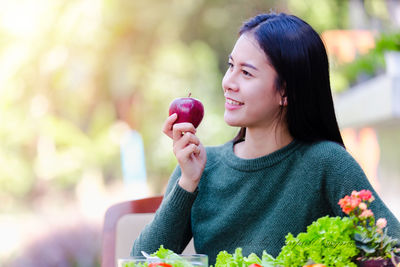 Young woman holding strawberry outdoors