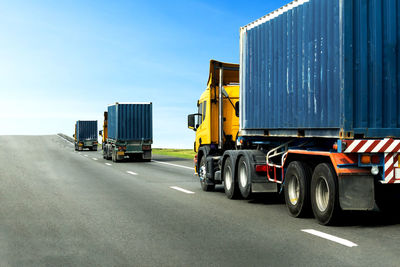 Vehicles on road against blue sky