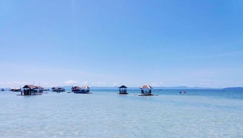 Boats sailing in sea against clear blue sky