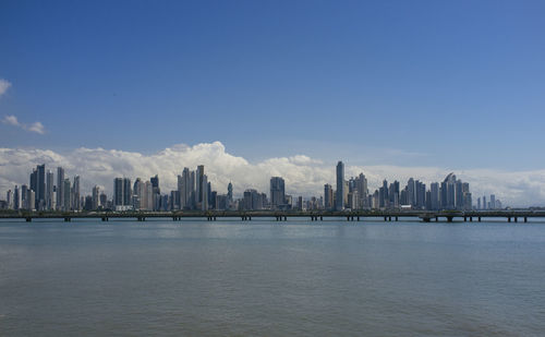 Sea by modern buildings against sky in city