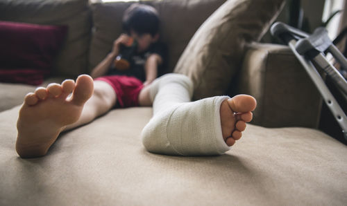 Boy with fractured leg sitting on sofa at home