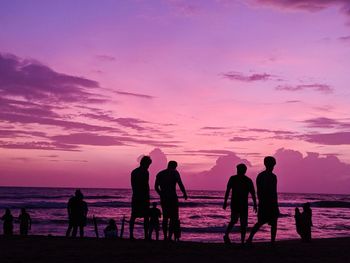 Silhouette people at beach against sky during sunset