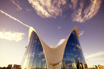 Low angle view of modern building against cloudy sky