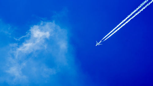 Airplane leaving vapor trail against blue sky