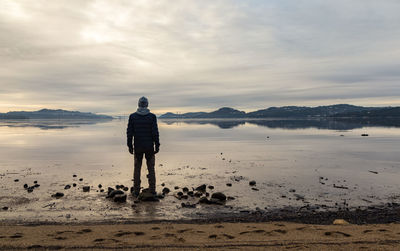 Rear view of man standing on beach against sky