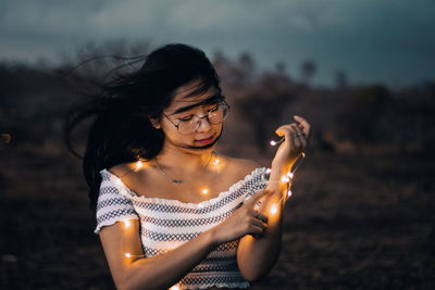 Midsection of woman holding illuminated lighting equipment