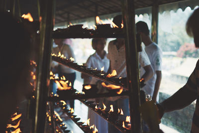 Close-up of people by lit tea lights at temple