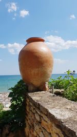 View of stone wall by sea against sky