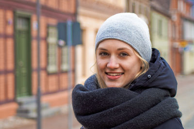 Close-up portrait of smiling young woman against buildings